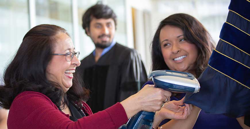 Coty Ventura steams a graduation gown while her daughter Bobbi assists.