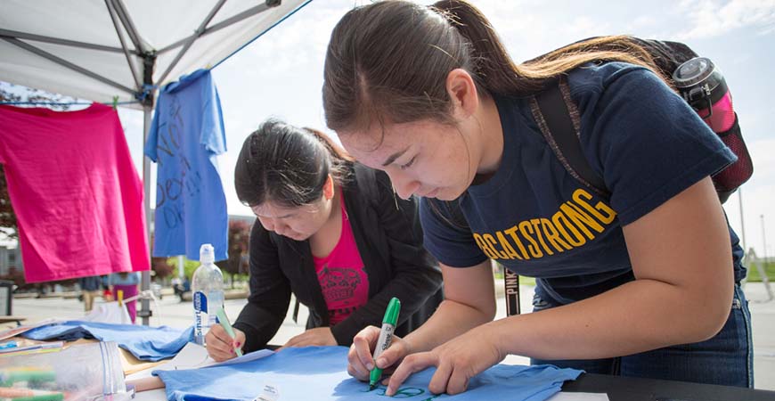 Two students decorate t-shirts for the Clothesline Project, one of many campus activities to commemorate Sexual Assault Awareness Month.