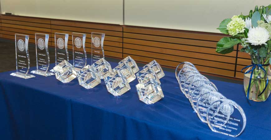 A long table holds a display of crystal awards.