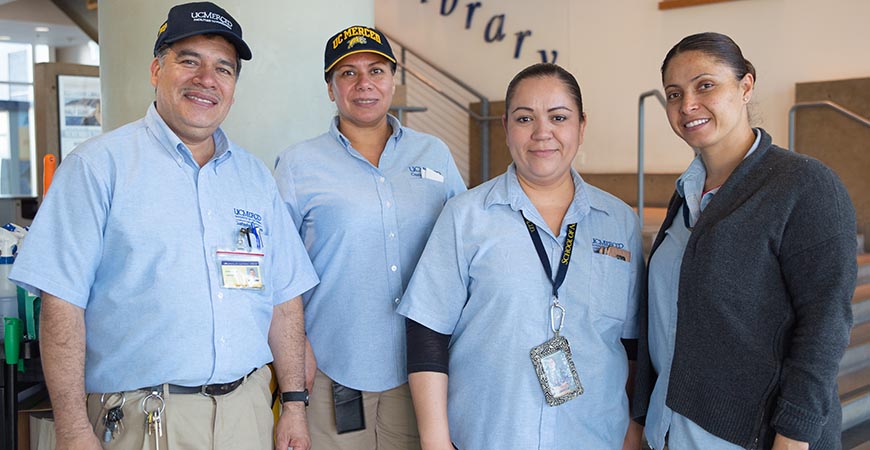 four individuals in blue uniforms smiling at the camera