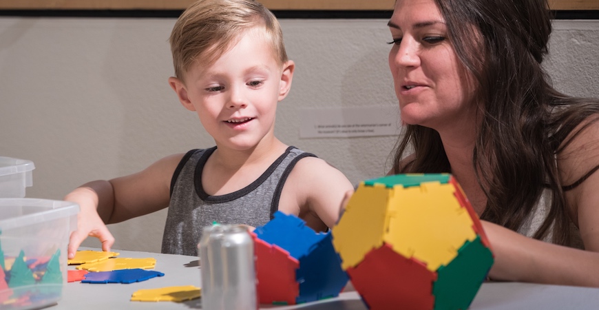 A young boy and a woman play with educational toys.