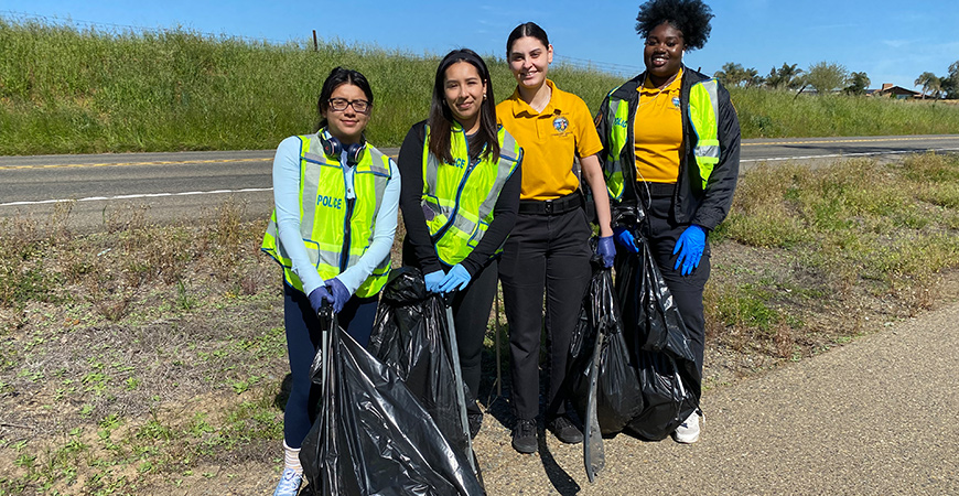 Four UC Merced students pose for a photo on the bike path along Lake Road.