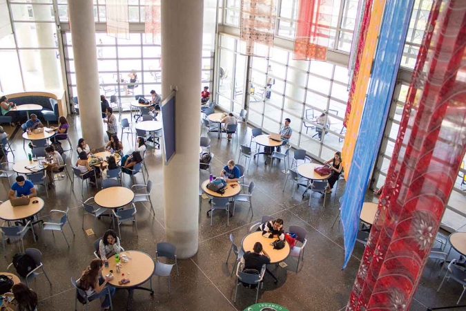 Aerial view of college students studying at round tables in a large space