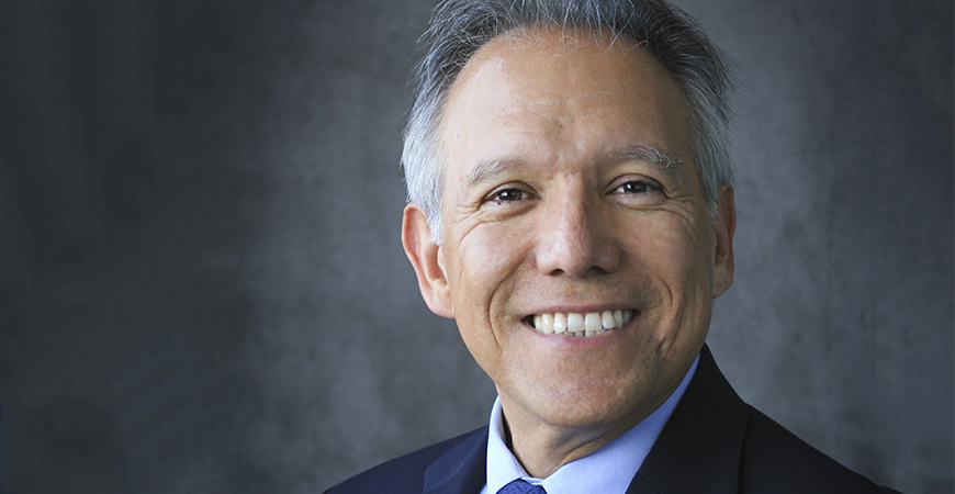 A portrait of a smiling professor, Juan Meza, in front of a gray background.