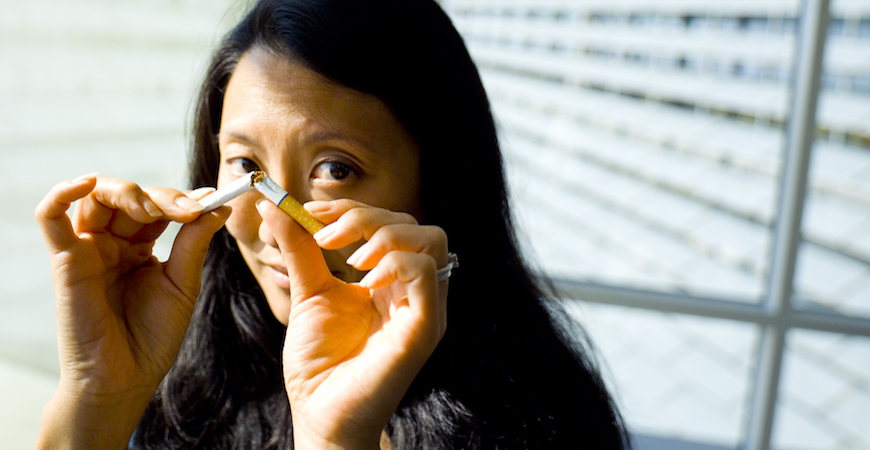 A woman holds a broken cigarette in her hands