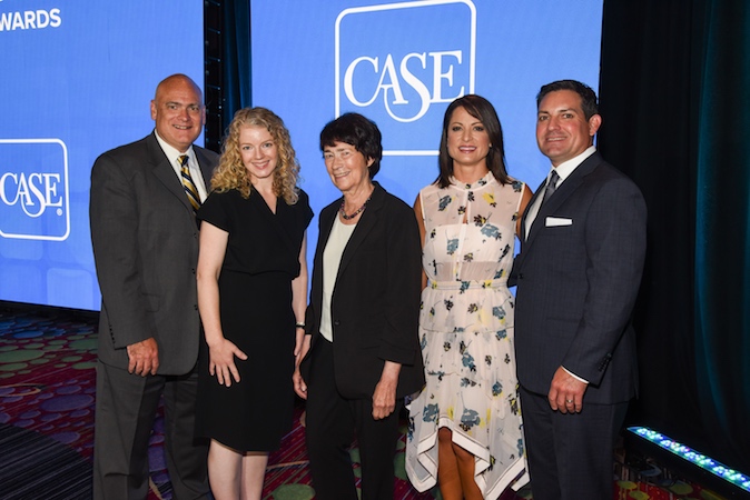 Two men and three women pose in front a large screen that reads "CASE" at the 2018 CASE awards.