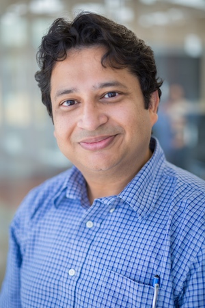 Headshot of a man in a blue button-down shirt.