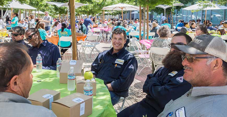 Several hundred UC Merced staff members, seated at tables outdoors, enjoy lunch during Staff Appreciation Week.