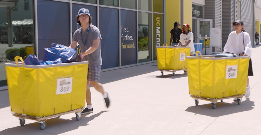 Photo shows people using carts to move items into dorms at UC Merced. 