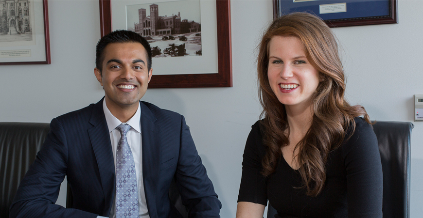 Ehsan Choudhry and Kristen Wanderlich pose seated at a conference table. 